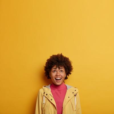 Happy Laughing Woman in Casual Jacket with Curly Hair Enjoying a Fun Advertisement – Free Download