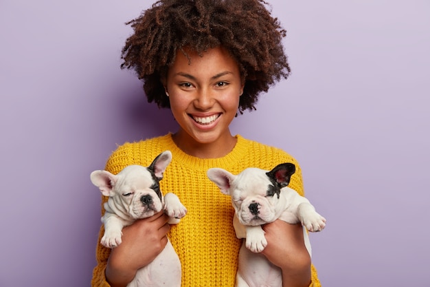 African American Woman in Yellow Sweater Holding Adorable Puppies – Free to Download
