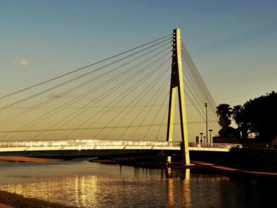 Stunning Sunset View of a Bridge, River, and Sea – Free Download