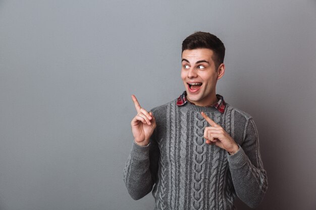 Surprised Happy Brunette Man in Sweater Pointing and Looking Aside – Free Download