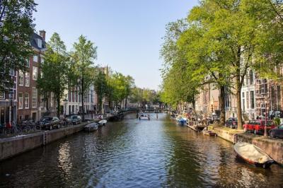 Boats in Amsterdam Canal Surrounded by Iconic City Buildings – Free Download