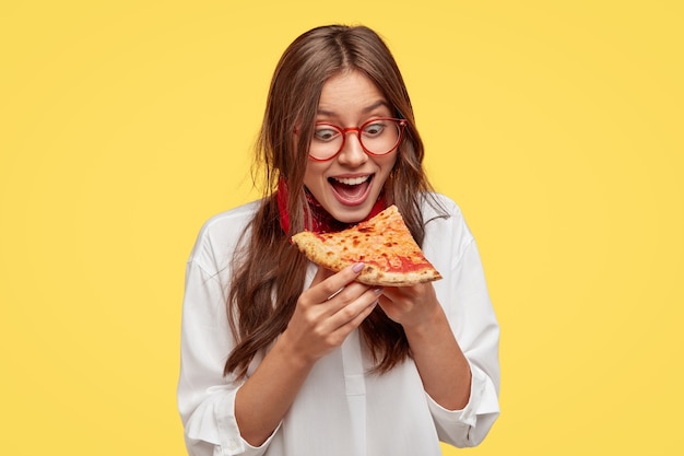 Hungry Student Eagerly Admiring Delicious Pizza in Front of Yellow Wall – Free Stock Photo for Download