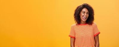 Confident Flirty Woman Winking Joyfully Against Orange Background – Free Download