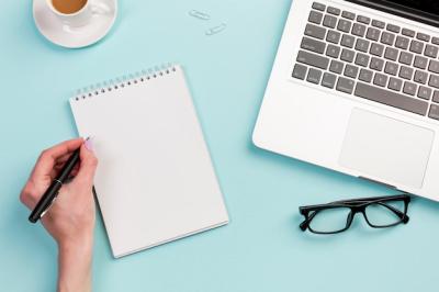 A Businesswoman Writing on a Spiral Notepad at the Office Desk – Free Stock Photo, Download Free
