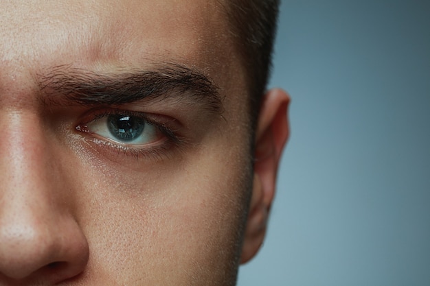 Close-up Portrait of a Young Caucasian Man’s Face and Blue Eye on Grey Background – Free Download