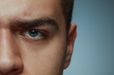Close-up Portrait of a Young Caucasian Man’s Face and Blue Eye on Grey Background – Free Download