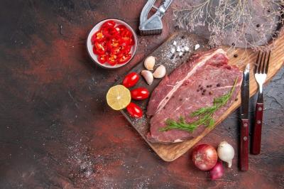 Overhead View of Red Meat on Wooden Cutting Board with Garlic, Green Lemon, Onion, Fork, and Knife – Free Download
