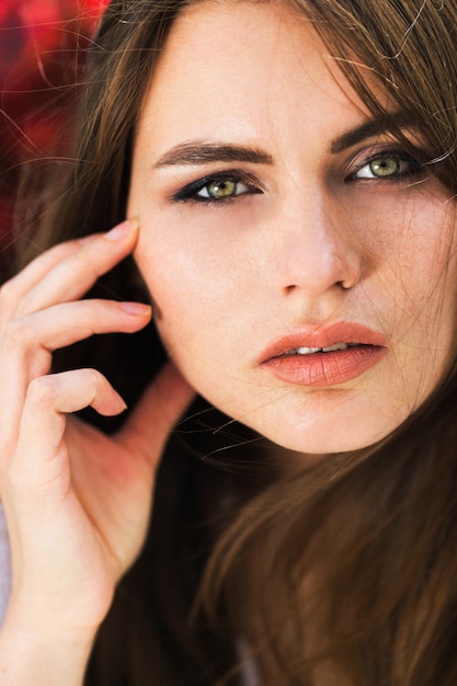 Stunning Green-Eyed Woman Surrounded by Red Flowers – Free Stock Photo for Download