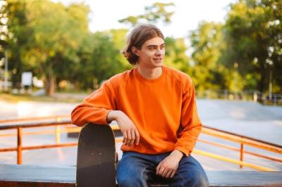 Young Smiling Skater in Orange Pullover at Modern Skatepark – Free Download