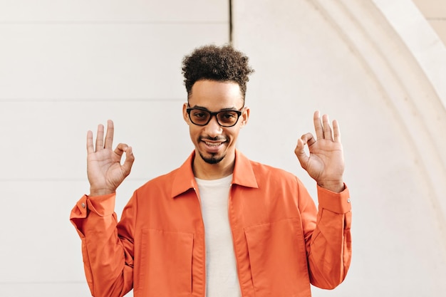 Darkskinned Bearded Man Smiling in White T-shirt and Orange Jacket – Free Download