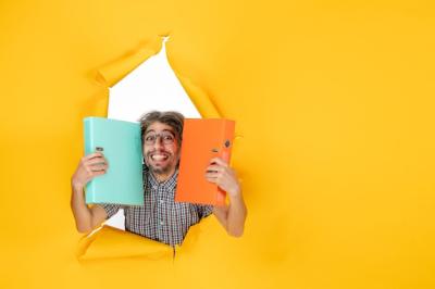 Young Male Holding Green File in Front View on Vibrant Yellow Background – Free Download Stock Photo