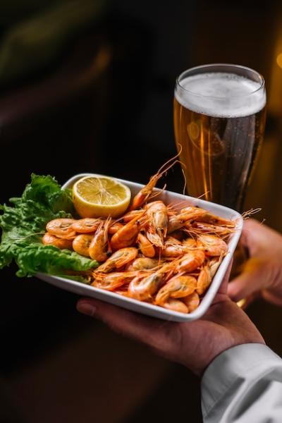 Side View of a Man Holding a Plate of Shrimps on Lettuce with Lemon – Free Download