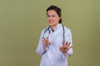 Smiling Young Doctor in Medical Gown with Stethoscope Against Green Wall – Free Download