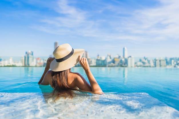 Beautiful Young Asian Woman Relaxing by Outdoor Swimming Pool with City View – Free Stock Photo for Download