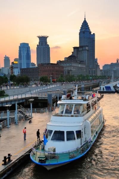 Boat on Huangpu River Against Shanghai Urban Architecture at Sunset – Free Download