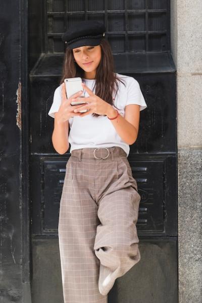 Smiling Young Woman Texting on Smartphone Against Black Wall – Free Download