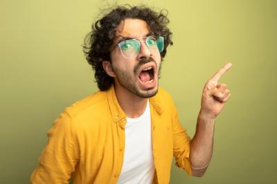 Impressed Young Handsome Caucasian Man Pointing at Side on Olive Green Wall – Free Download