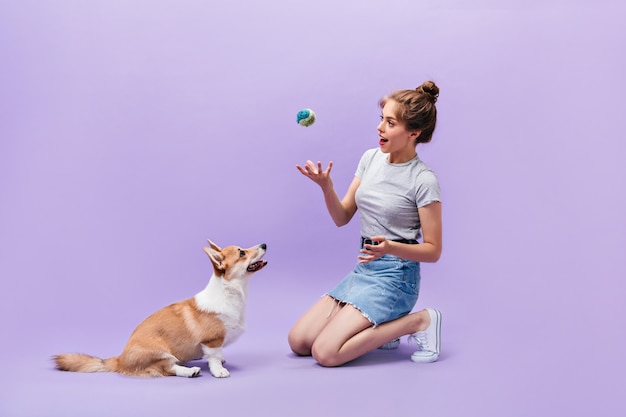 Happy Young Woman Playing with Corgi on Purple Background – Free Download