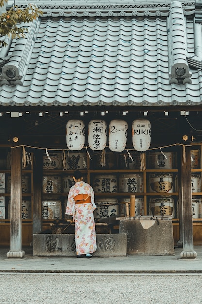 Orange and White Kimono Dress on a Woman Near a House – Free to Download