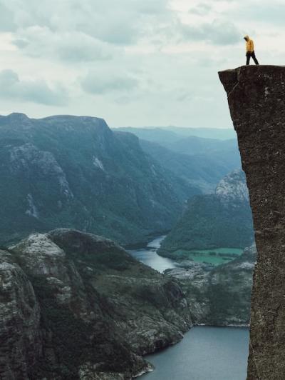 Man in a Yellow Jacket on a Rock – Free Stock Photo for Download