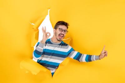 Young Man Making Okay Sign Through Hole in Yellow Paper Wall – Free Stock Photo, Download for Free