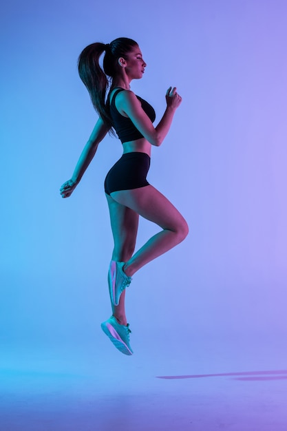 Strong Young Sports Woman Jumping Against a Purple Background – Free to Download