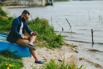 Guy Sitting on Wooden Boat Using His Phone – Free Download