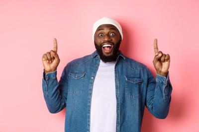 Cheerful Black Man Offering a Fantastic Promo, Smiling Against a Pink Background – Free Download