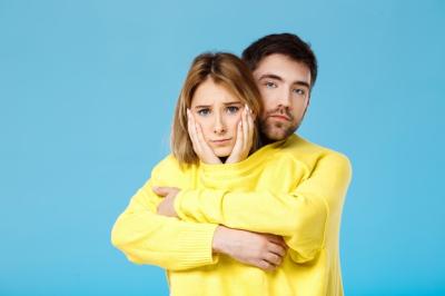 Young Beautiful Couple Embracing in a Yellow Sweater Against a Blue Wall – Free Stock Photo for Download