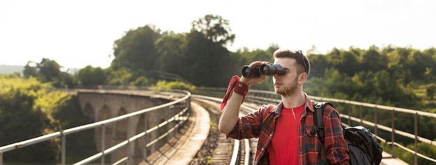 Portrait of a Man with a Backpack Using Binoculars – Free Download