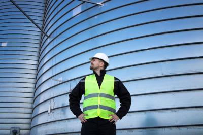 Portrait of an Industrial Worker by a Metal Silo Storage Tank – Free to Download