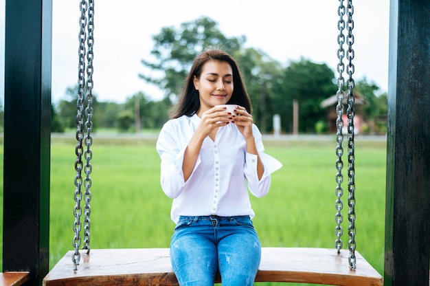 Woman Sitting on a Swing Enjoying Coffee – Free Download