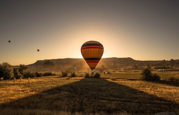 Colorful Hot Air Balloon in a Scenic Field at Sunset – Free Download