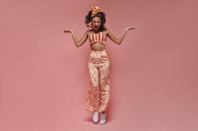 Bright Lady Jumping in Orange Headband and Pink Printed Trousers – Free Stock Photo for Download