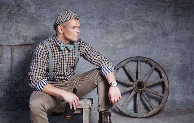 Handsome Guy in Checkered Shirt with Blue Bow Tie Posing Against Concrete Wall – Free Stock Photo for Download