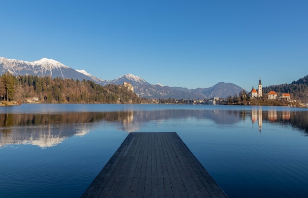 Reflection of Mountains and Old Buildings in Lake with Wooden Pier – Free Download