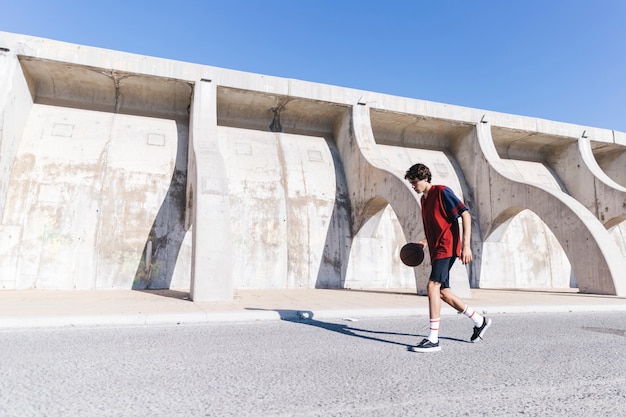 Teen Practicing Basketball Against a Wall – Free Download