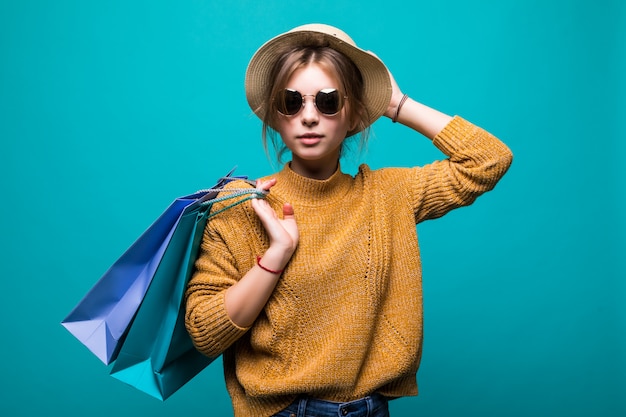 Young Teen Woman in Sunglasses and Hat with Shopping Bags Against a Green Wall – Free Stock Photo for Download