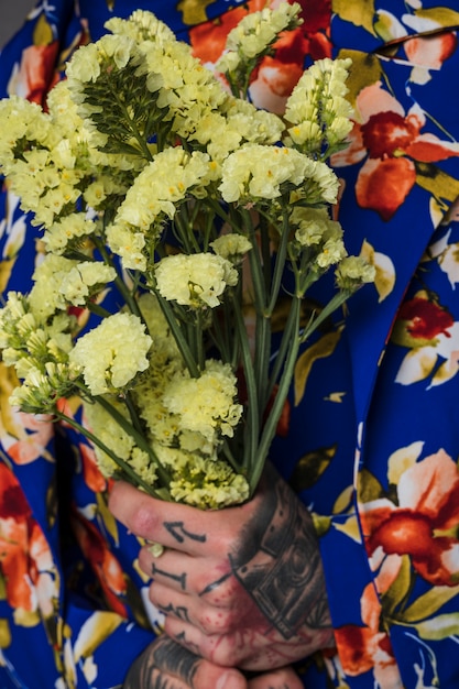 Close-up of a Man with a Tattoo Holding a Limonium Flower – Free Download