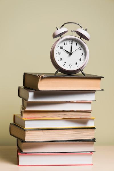 An Alarm Clock on Stacked Books Over a Wooden Desk – Free Stock Photo for Download