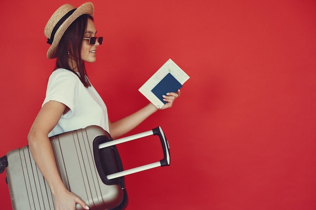 Chic Travel Photo: Girl Posing with Travel Gear Against a Red Wall – Free Download