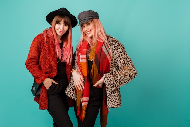 Two Beautiful Women in Stylish Faux Fur Coats and Wool Scarves on Turquoise Wall – Free Download