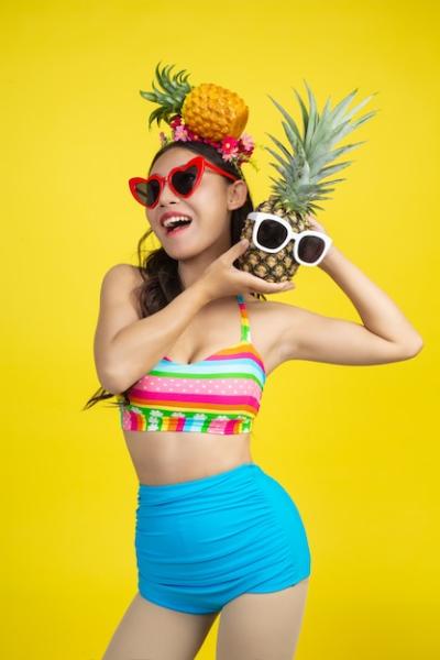 Beautiful Woman in a Swimsuit Holding a Pineapple on Yellow Background – Free Download