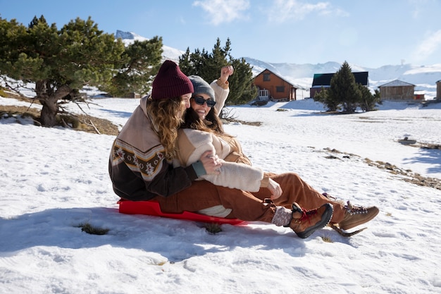 Side View of Two Female Lovers on a Sleigh During Winter Trip – Free Download