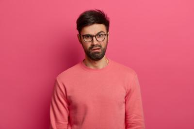 Displeased Young Man with Glasses and Jumper Against Pink Wall – Free Stock Photo for Download