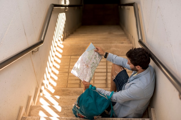 Traveler Sitting on Stairs and Looking at Map – Free Stock Photo for Download