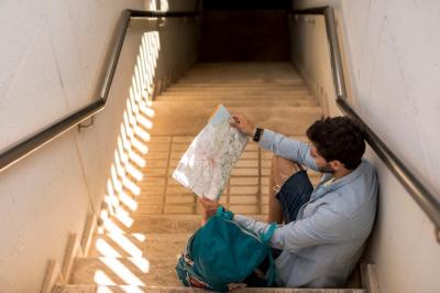 Traveler Sitting on Stairs and Looking at Map – Free Stock Photo for Download