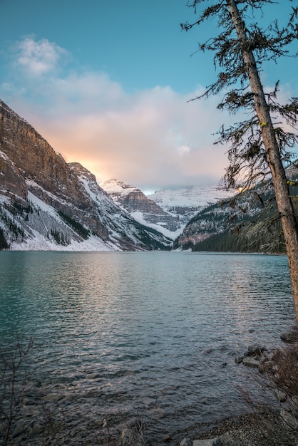 Vertical Shot of a Lake Surrounded by Snowy Mountains and a Bright Sky – Free Download