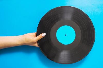 Female Hands Holding a Vinyl Record on Blue Background – Free Download