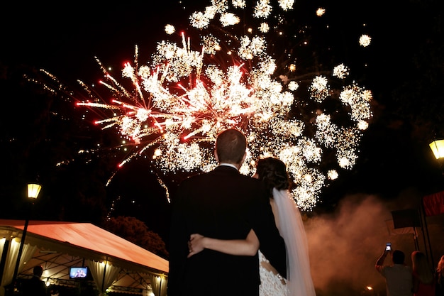 Happy Bride and Groom Embrace Under Colorful Fireworks – Free Download